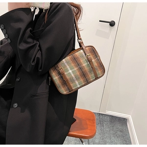 Detail of vintage plaid shoulder bag featuring tweed texture and brown leather straps