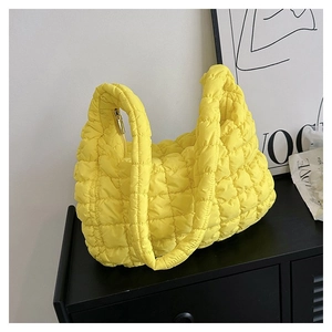 Close-up of bright yellow quilted cloud tote bag with gold zipper and puffy texture