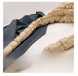 Detail view of the wide quilted shoulder strap on a beige cloud bag with a zipper