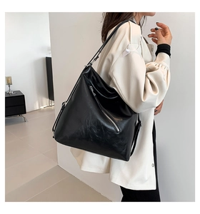 Détail du sac cabas noir en cuir PU brillant avec fermeture éclair argentée sur trench