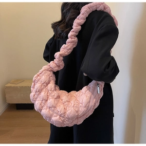 Pink quilted hobo bag with ruched strap and diamond texture shown on a black coat