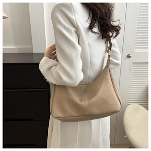 Detail of minimalist beige PU leather tote bag with lychee texture on model shoulder