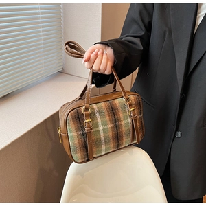 Detail of winter plaid wool and brown leather shoulder bag with gold hardware accents