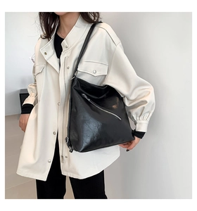 Vue détaillée du sac hobo en cuir PU noir avec fermeture éclair diagonale porté à l'épaule