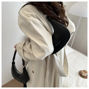 Detailed view of black PU leather half-moon bags with FASHION logo on a soft background