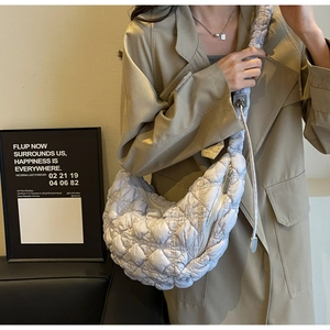 Detail of light beige quilted puffer shoulder bag with ruched strap and square stitching
