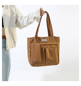 Detail of earthy brown nylon tote bag with multiple front pockets and fashion tag
