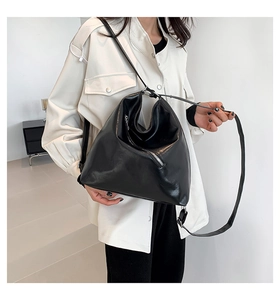 Sac hobo chic en cuir PU noir brillant porté par un mannequin montrant la bandoulière réglable