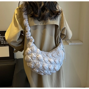 Detailed view of grey quilted bubble crossbody bag texture on model wearing trench coat