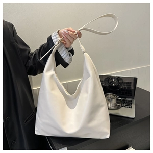 Detail of minimalist cream PU leather hobo bag showing supple texture and wide strap