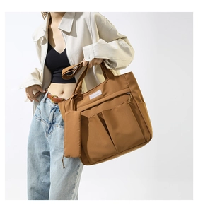 Detail of brown nylon tote bag with multiple pockets and white fashion label on surface