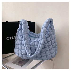Detail of light blue quilted bubble tote bag featuring soft puffer texture and wide straps