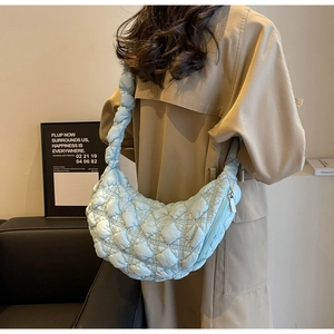 Detailed view of light blue quilted fabric crescent bag with stylish scrunchie shoulder strap