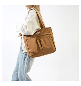 Detail of caramel brown nylon tote bag with utility pockets and a small matching pouch