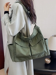 Army green large canvas messenger bag with multi-pockets and wide strap on model