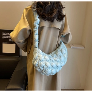 Close-up of light blue quilted bubble bag with padded straps and soft nylon texture