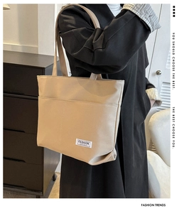 Dettaglio della borsa tote in tela beige con etichetta Fashion Instinct e tasca frontale