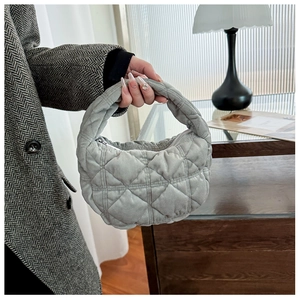 Close-up of light grey quilted handbag featuring classic diamond stitching and padded handle