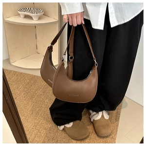 Detailed view of two brown crescent hobo bags with fashion logo in a stylish setting