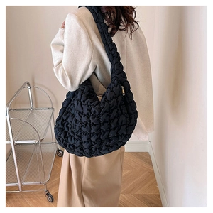 Detailed close-up of large black quilted cloud bag with puffy texture and gold zipper