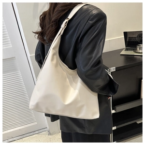 Chic cream-colored PU leather hobo bag styled on a black leather jacket with wide strap