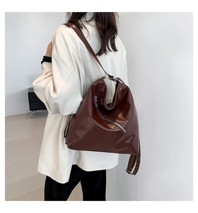 Détail d'un sac à bandoulière en PU marron foncé brillant avec fermeture éclair décorative