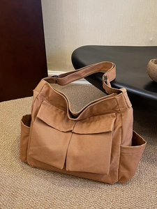 Minimalist canvas tote bag with large front pockets and adjustable strap in khaki brown