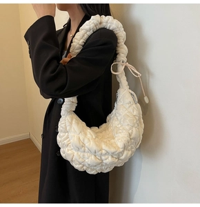 Detailed close-up of quilted pleated cloud bag with bow knots and ruffled shoulder strap