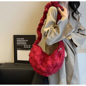 Detail of red quilted bubble fabric on a crescent shoulder bag with wide strap