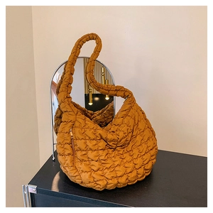 Detail view of the caramel quilted puffer bag with puffy texture and side zipper