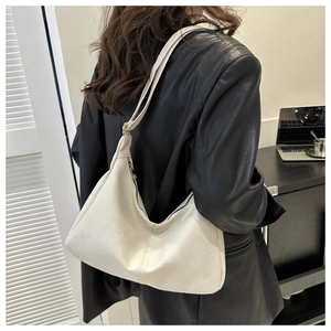 Chic cream-white PU leather hobo bag with adjustable strap worn on the shoulder