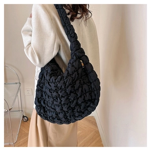 Macro detail of the black quilted cloud bag texture with golden zipper on a nylon shoulder bag