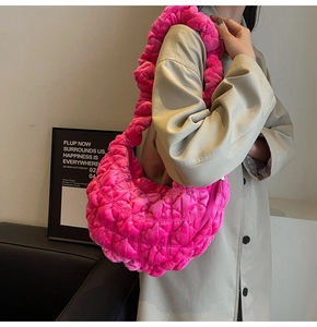 Detailed side view of bright pink quilted plush handbag with thick padded shoulder strap