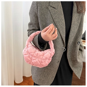 Close-up of pink quilted puffer mini handbag held by model wearing a dark suit