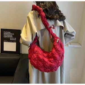 Model wearing a large red quilted hobo bag with cloud-style pleated shoulder straps