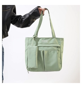 Detail of light green nylon tote bag featuring front pockets and hanging mini pouch