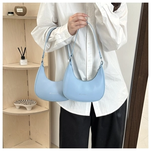 Detail of light blue hobo bag with Fashion print held by model in modern setting