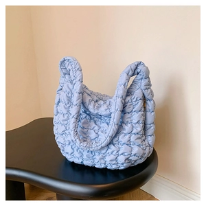 Detailed close-up of light blue quilted fabric textures and puffer cloud hobo bag seams