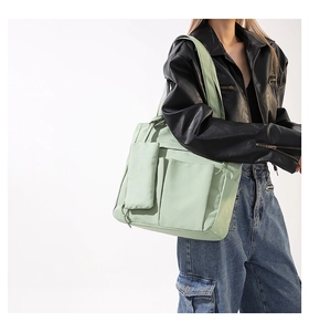 Detail of mint green nylon tote bag featuring functional front pockets and a mini pouch