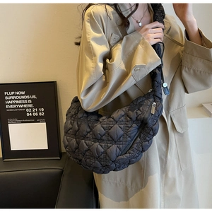 Chic black quilted half-moon shoulder bag styled with a classic khaki trench coat