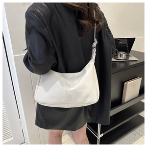 White PU leather hobo bag shown from a side view on a model in a minimalist setting