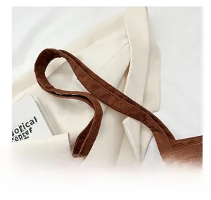 Detailed macro view of soft wide-ribbed corduroy handles on a dark brown tote bag