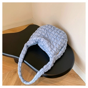 Macro shot of light blue quilted bubble fabric texture on a casual crossbody bag