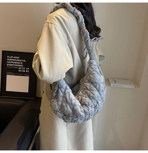 Detail of grey quilted hobo bag with a scrunchie shoulder strap and crescent design