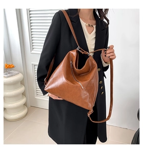 Détail d'un sac à épaule en cuir PU marron caramel avec des fermetures éclair argentées