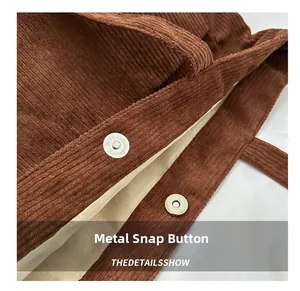 Detail of metal magnetic closure on brown corduroy tote bag with beige lining