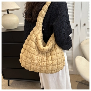 Sac fourre-tout matelassé beige à motif de losanges porté par un mannequin