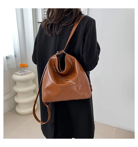 Sac Hobo caramel porté sur un manteau noir dans un décor élégant et minimaliste