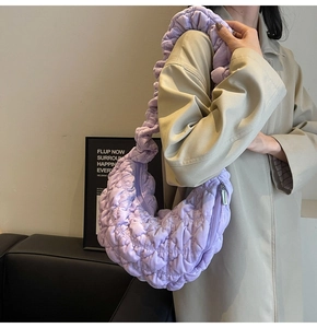 Detail view of purple quilted crescent bag with ruffled strap and waffle texture