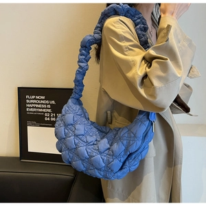 Detail of royal blue quilted crescent bag with ruffled shoulder strap and puffy fabric
